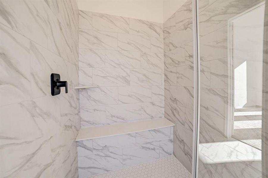 View of the large walk in shower featuring two tone tile selections in the primary bath.