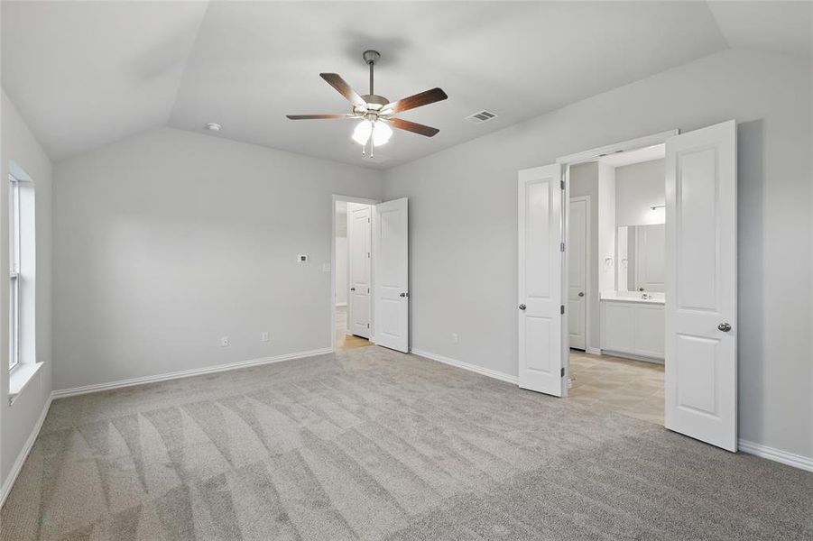 Unfurnished bedroom featuring lofted ceiling, light colored carpet, and a ceiling fan Unfurnished bedroom featuring lofted ceiling, light colored carpet, and a ceiling fan