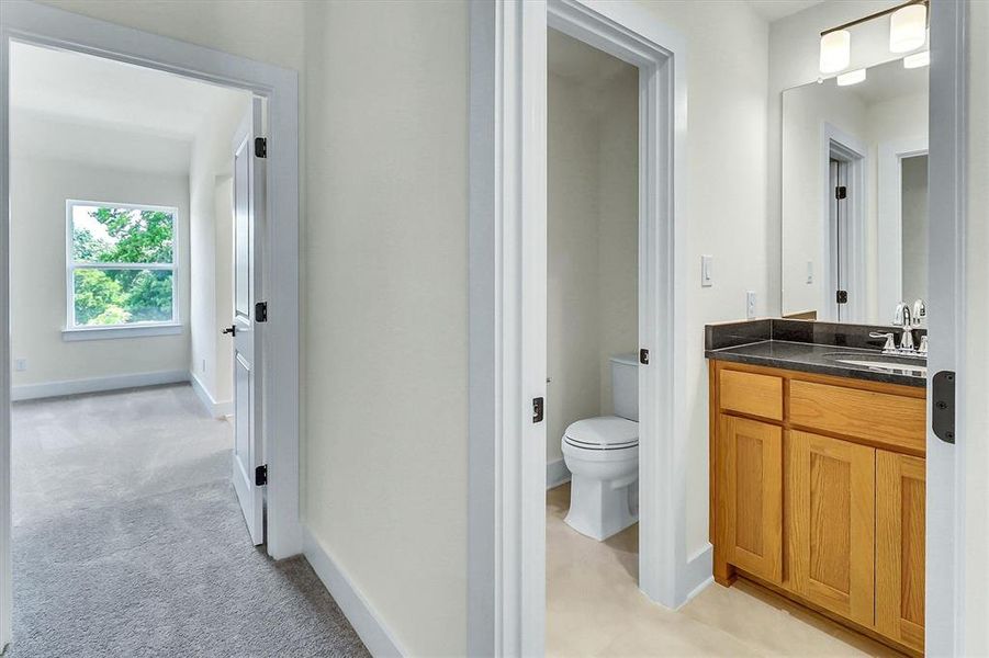Bathroom vanity with a wood-finish cabinet, dark countertop, and chrome faucet Bathroom vanity with a wood-finish cabinet, dark countertop, and chrome faucet