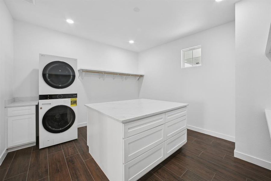 Washroom with wood tiled floors, estacked washer and dryer, cabinet space, and recessed lighting