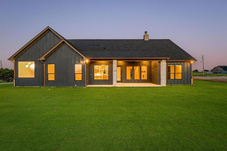 Back house at dusk with a yard