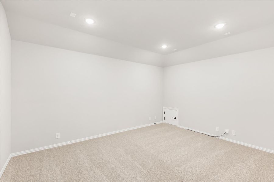 Empty room with beige carpet, white walls, recessed lighting, and a small door