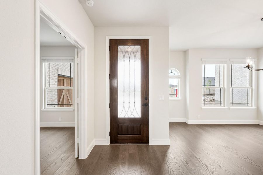 Home entryway with dark wood front door featuring decorative glass panel and hardwood floors
