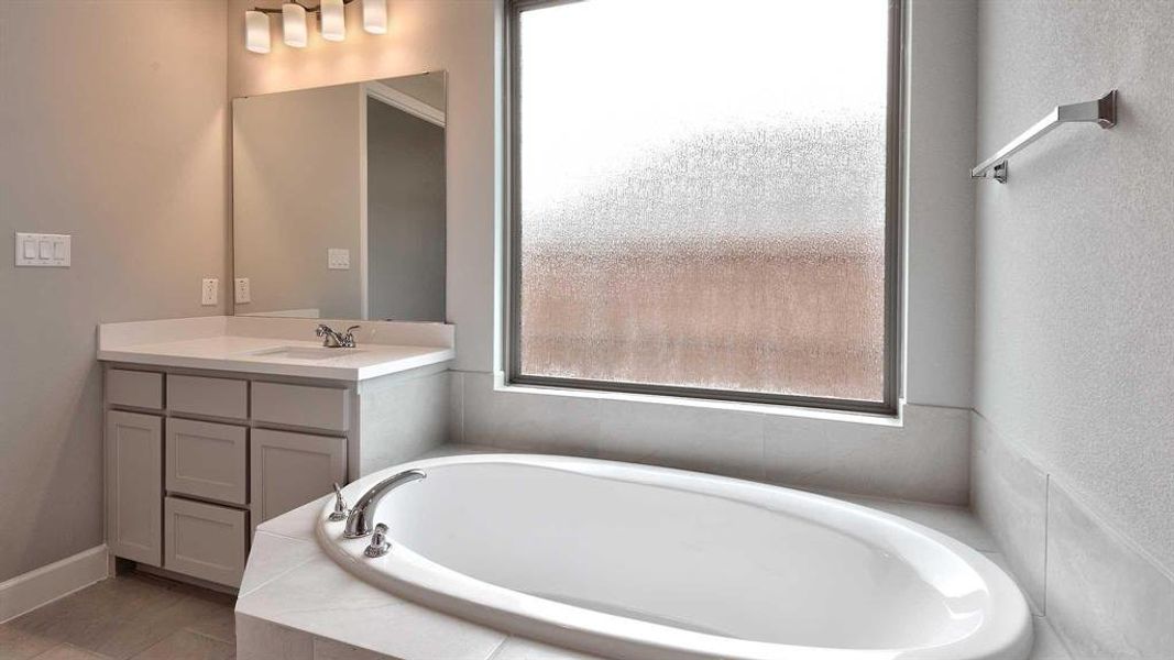 Bathroom with vanity and tiled bath