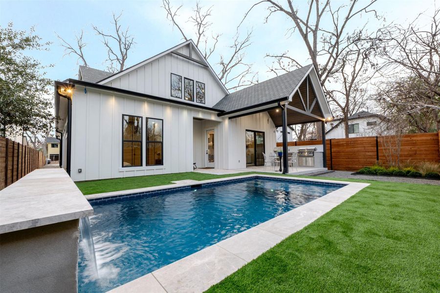 Rear view of house with a fenced backyard, board and batten siding, a patio area, and exterior kitchen