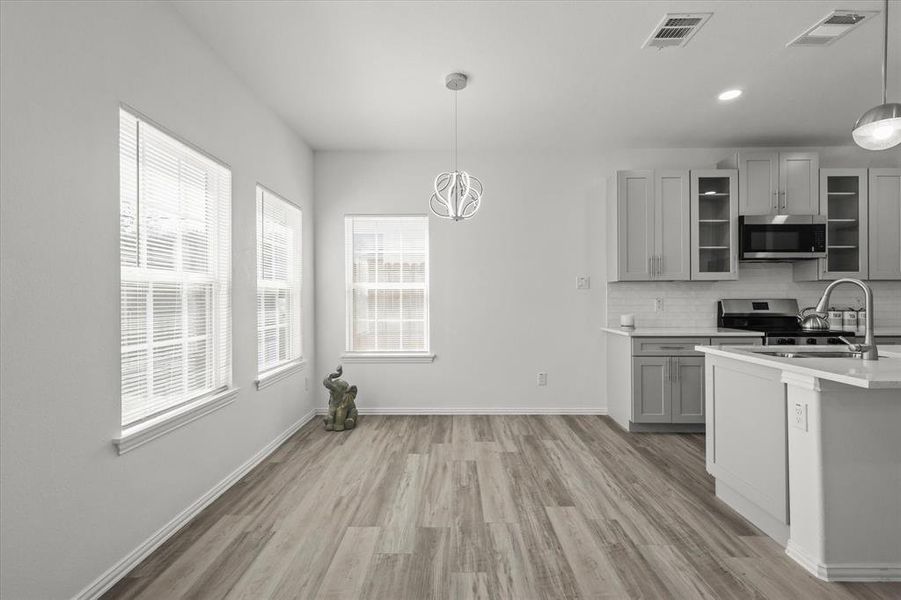 Kitchen featuring tasteful backsplash, visible vents, gray cabinetry, appliances with stainless steel finishes, and a sink