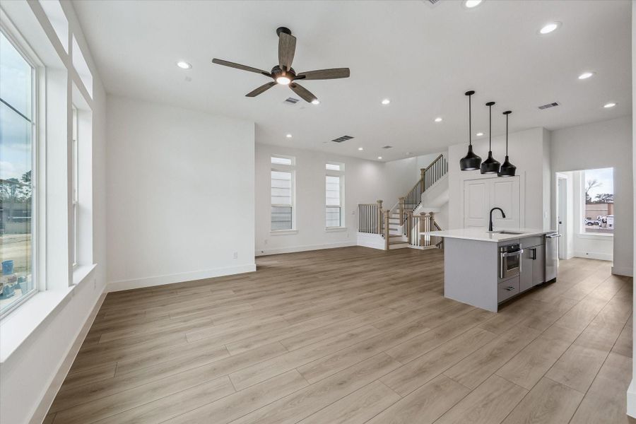 Main living area with ceiling fan, bright windows, and kitchen connection Main living area with ceiling fan, bright windows, and kitchen connection