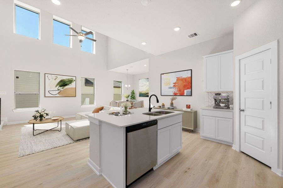 This stunning open-concept kitchen seamlessly connects to the living area, featuring soaring ceilings and abundant natural light. With a large island, modern fixtures, and crisp white cabinetry, this space is perfect for both everyday living and entertaining.