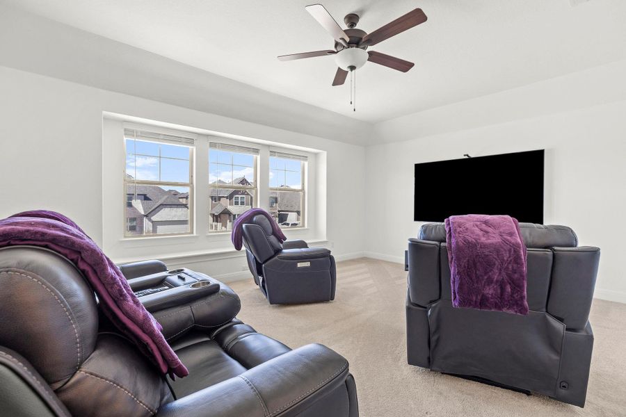 Living room featuring light carpet and a ceiling fan