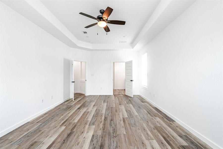 A spacious bedroom showcasing a vaulted ceiling with a ceiling fan, complemented by sleek vinyl plank flooring. A spacious bedroom showcasing a vaulted ceiling with a ceiling fan, complemented by sleek vinyl plank flooring.