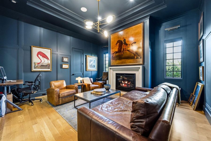 Sophisticated study wrapped in rich, moody millwork with coffered ceiling detail and a sleek fireplace creating a warm, intimate setting. Designer lighting and curated finishes elevate the space—ideal for a home office, library, or refined lounge.