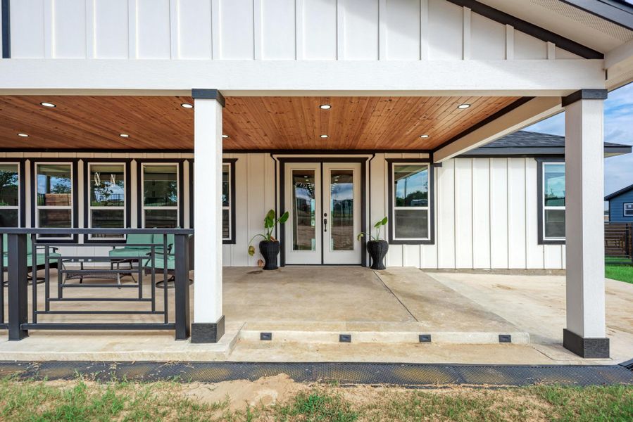 A spacious covered back porch features a warm wood-plank ceiling and concrete flooring. A spacious covered back porch features a warm wood-plank ceiling and concrete flooring.