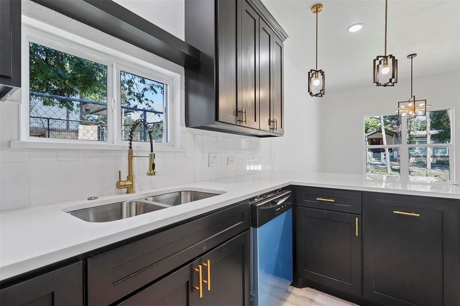 Kitchen featuring backsplash, sink, dark brown cabinetry, dishwasher, and hanging light fixtures