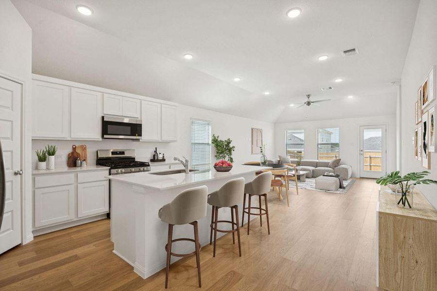 Kitchen with light wood-style flooring, a breakfast bar area, white cabinetry, appliances with stainless steel finishes, and light countertops