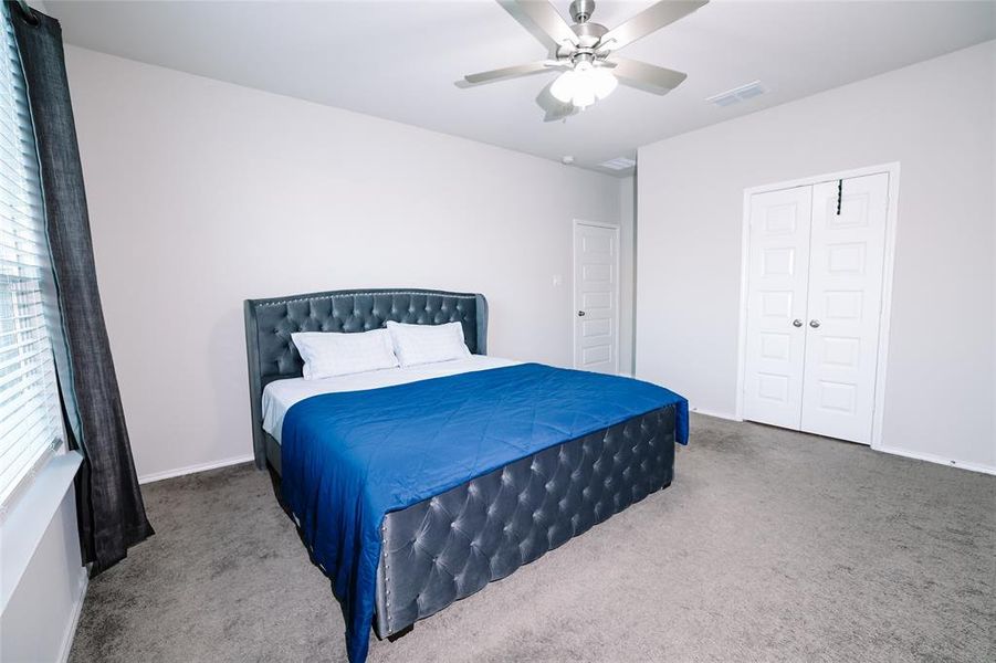 Carpeted bedroom featuring ceiling fan and a closet