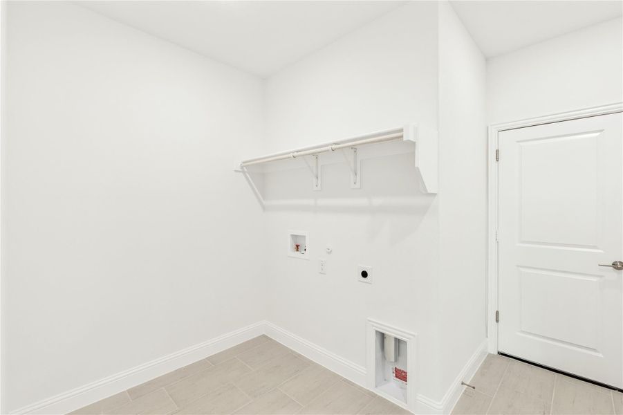 Empty laundry room with wall shelf, washer and dryer hookups, and tile flooring