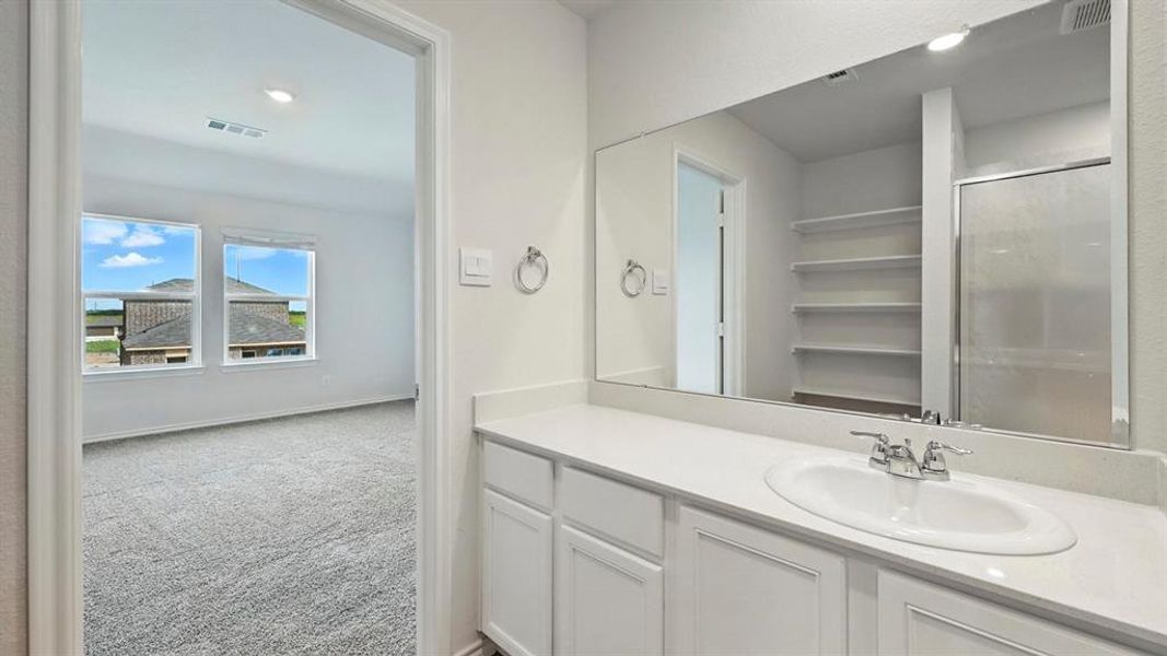 Bathroom vanity featuring a single basin sink, white cabinetry with silver hardware, and a large mirror