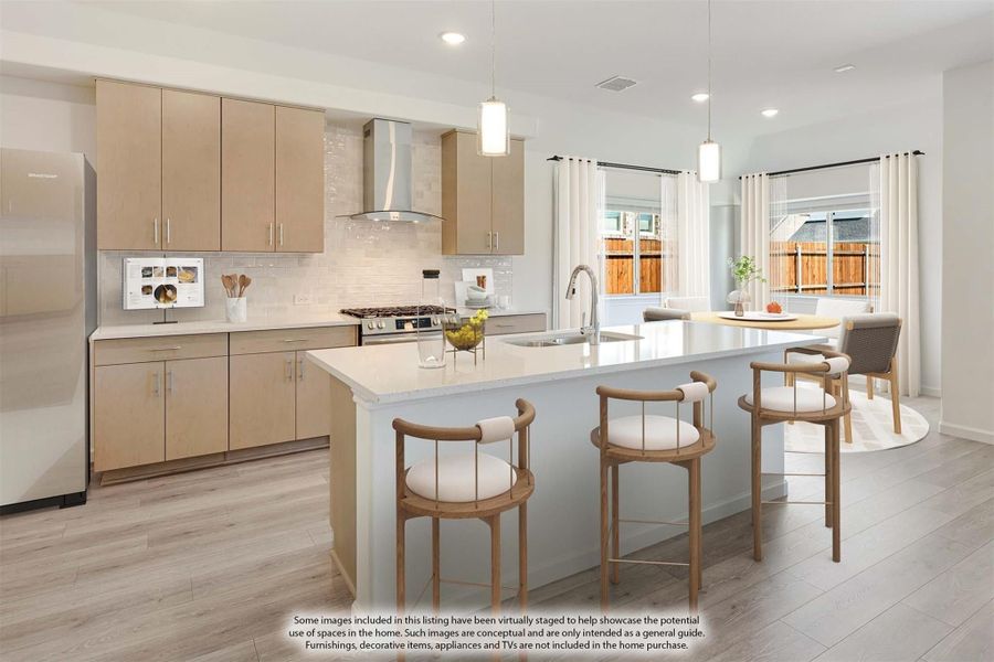 Kitchen with light wood cabinets, large island with seating, stainless range, and pendant lights over wood-look floors Kitchen with light wood cabinets, large island with seating, stainless range, and pendant lights over wood-look floors
