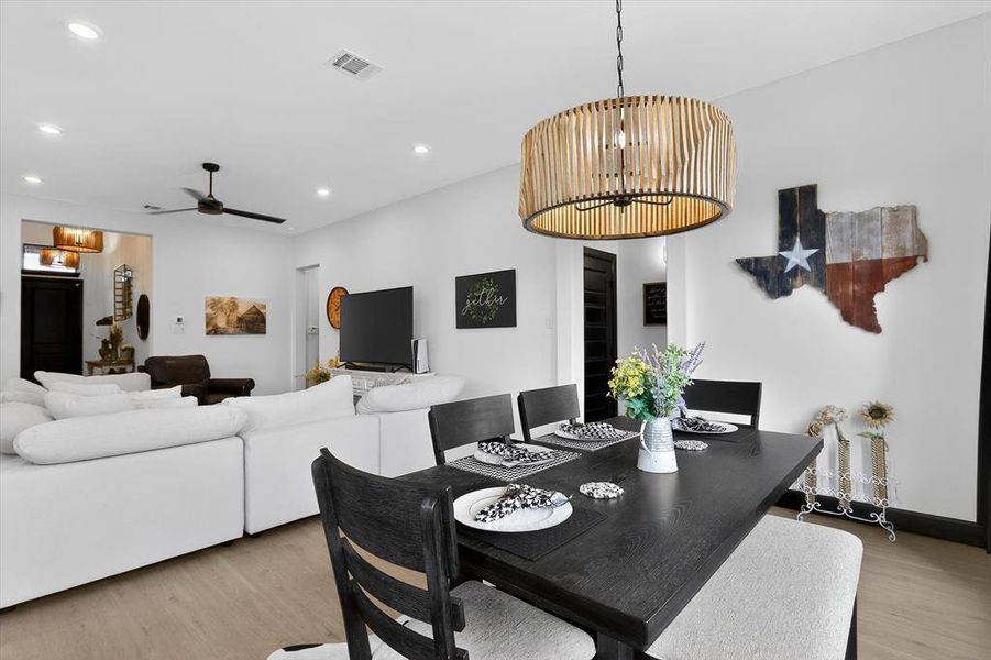 Open-concept living and dining area featuring light wood-finish flooring, recessed lighting, and a modern ceiling fan