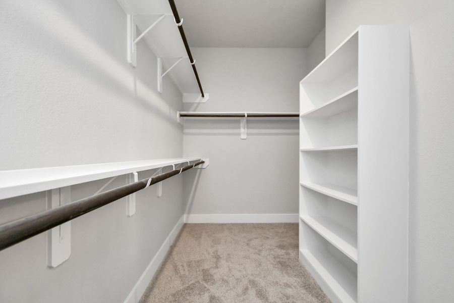 Step into a walk-in closet that defines luxury and functionality. This generously sized space boasts built-in shelving, providing ample room for organization. Sample photo of completed home with similar plan. As built color and selections will vary. Step into a walk-in closet that defines luxury and functionality. This generously sized space boasts built-in shelving, providing ample room for organization. Sample photo of completed home with similar plan. As built color and selections will vary.