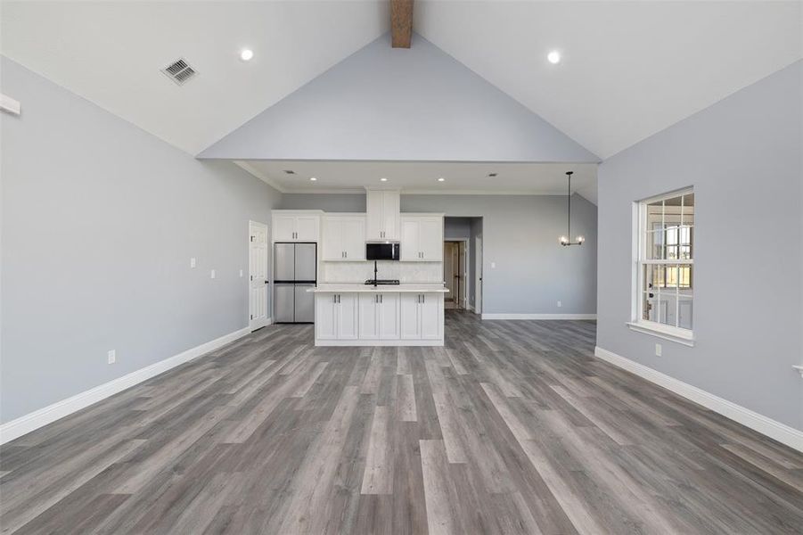 Unfurnished living room with beam ceiling, recessed lighting, high vaulted ceiling, and dark wood-type flooring Unfurnished living room with beam ceiling, recessed lighting, high vaulted ceiling, and dark wood-type flooring
