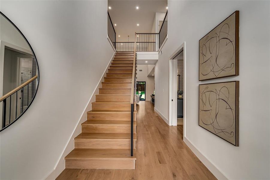 Stairs with a towering ceiling, wood finished floors, and recessed lighting Stairs with a towering ceiling, wood finished floors, and recessed lighting
