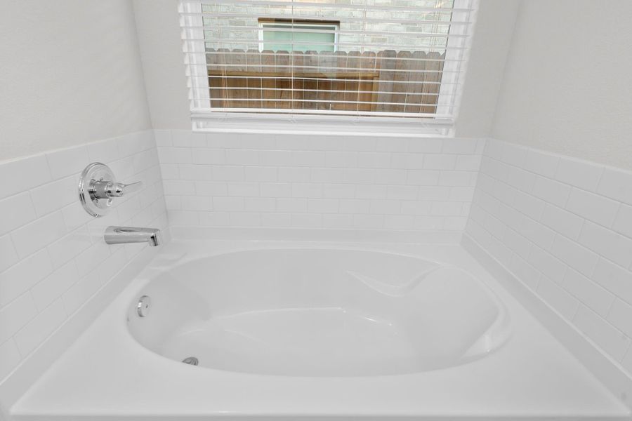 The primary bathroom features a deep soaking tub positioned beneath a large window that fills the space with soft natural light. It offers the perfect place to relax after a long day and enjoy a peaceful retreat right at home. Bubble me away! The primary bathroom features a deep soaking tub positioned beneath a large window that fills the space with soft natural light. It offers the perfect place to relax after a long day and enjoy a peaceful retreat right at home. Bubble me away!