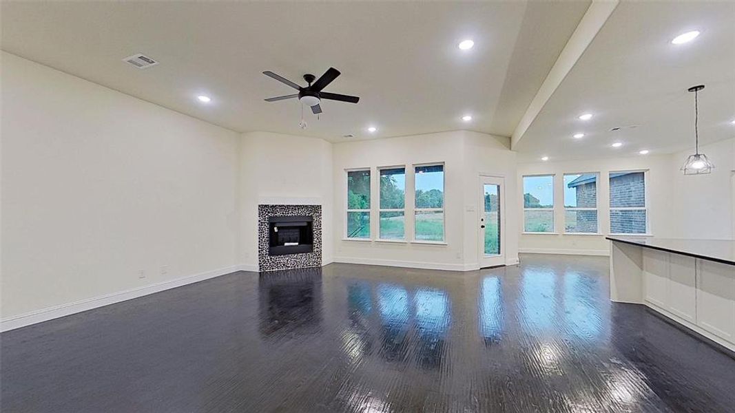 Unfurnished living room with dark wood-style floors, a tiled fireplace, a ceiling fan, and recessed lighting Unfurnished living room with dark wood-style floors, a tiled fireplace, a ceiling fan, and recessed lighting