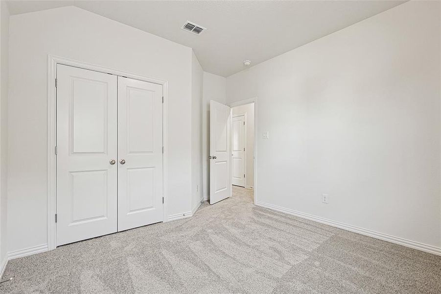 Unfurnished bedroom with light colored carpet and a closet