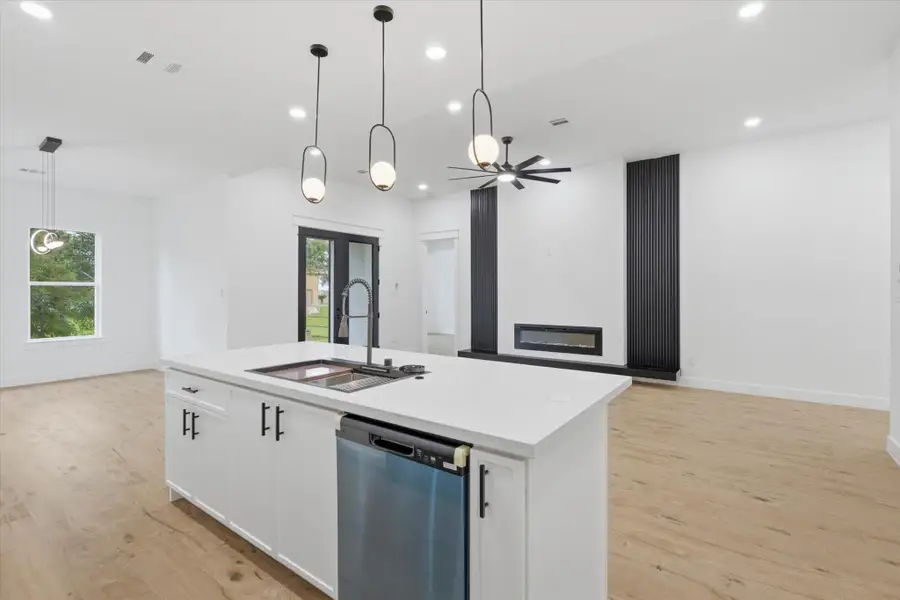 The Ultimate Prep Zone. This massive quartz waterfall island is a chef's dream, complete with a professional-grade workstation sink with built-in accessories, an industrial pull-down faucet, a built-in dishwasher, and elegant modern pendant lighting.