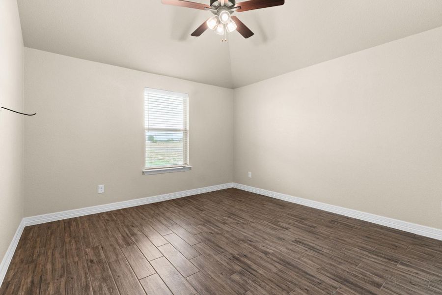 Spare room featuring dark wood like tile floors, lofted ceiling, and a ceiling fan Spare room featuring dark wood like tile floors, lofted ceiling, and a ceiling fan