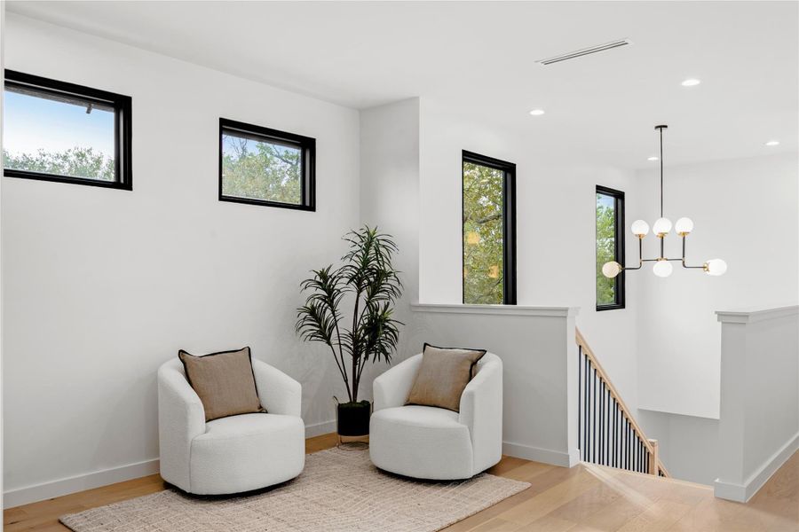 Sitting room with an upstairs landing, wood finished floors, recessed lighting, and a chandelier