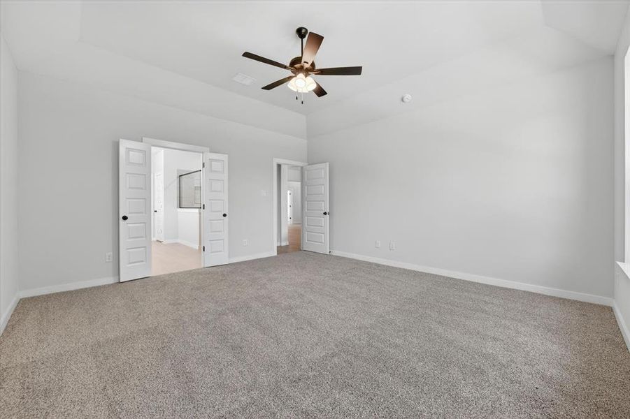 Spacious room featuring vaulted ceilings, neutral-toned carpet flooring, and white walls