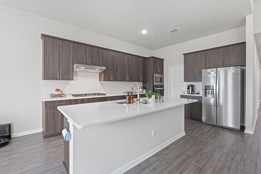 Kitchen with tasteful backsplash, dark brown cabinets, a sink, appliances with stainless steel finishes, and visible vents Kitchen with tasteful backsplash, dark brown cabinets, a sink, appliances with stainless steel finishes, and visible vents