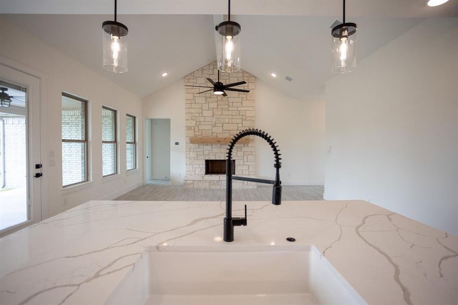 Kitchen view of ceiling fan, light stone countertops, pendant lighting, a stone fireplace, and recessed lighting Kitchen view of ceiling fan, light stone countertops, pendant lighting, a stone fireplace, and recessed lighting