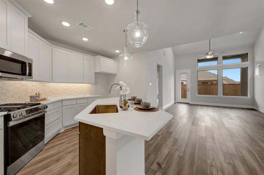 Kitchen island with a copper-tone sink, white countertops, and pendant lighting
