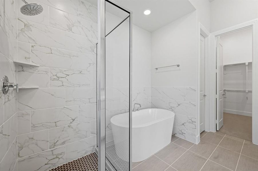 Full bathroom with tile walls, a freestanding tub, a spacious closet, a shower stall, and light tile patterned floors Full bathroom with tile walls, a freestanding tub, a spacious closet, a shower stall, and light tile patterned floors