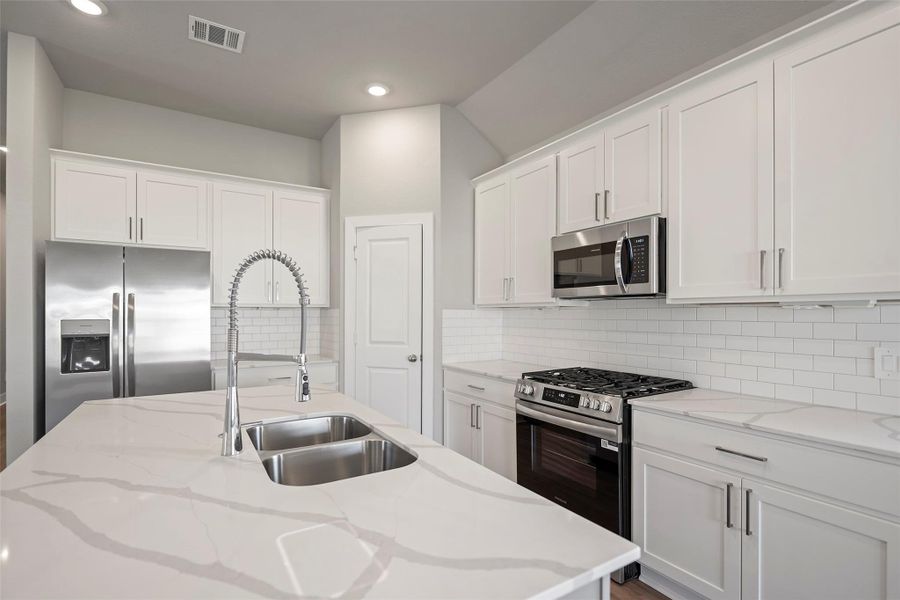 Gorgeous chef’s kitchen with gleaming counters, ample cabinetry, and stainless steel appliances.