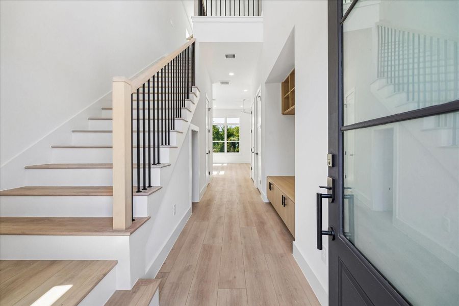 A soaring two story foyer introduces the home’s clean architectural lines, wide plank flooring, and abundant natural light.