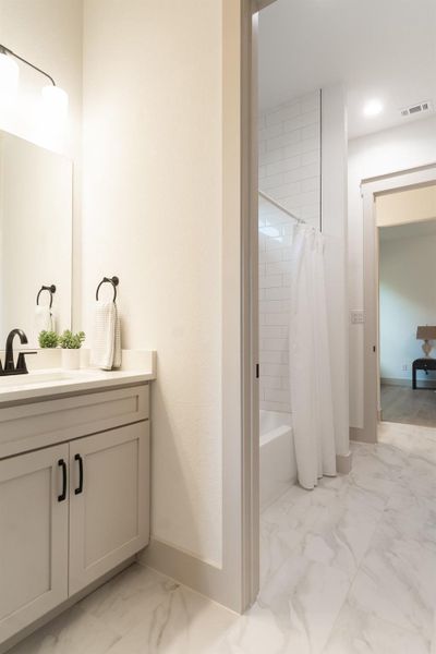 Bathroom with marble finish flooring, vanity, and shower / tub combo Bathroom with marble finish flooring, vanity, and shower / tub combo