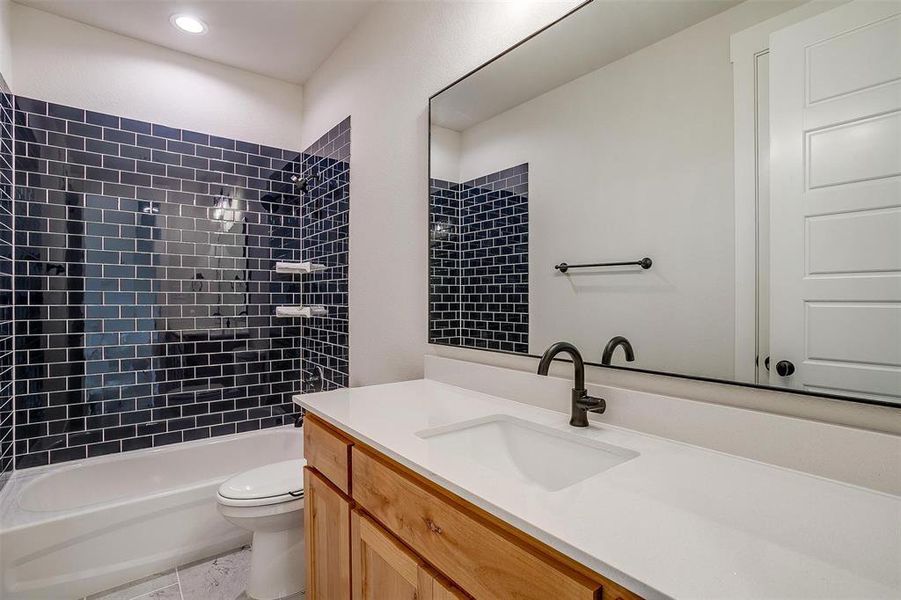 Full bathroom featuring tiled shower / bath, toilet, vanity with extensive cabinet space, and tile floors