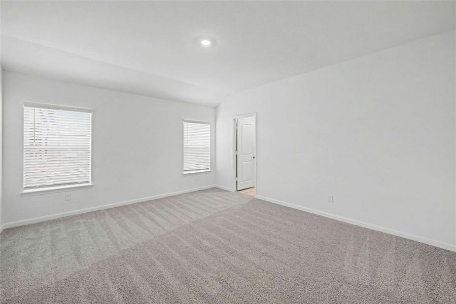 A spacious, naturally illuminated room featuring plush carpeting and modern recessed lighting.