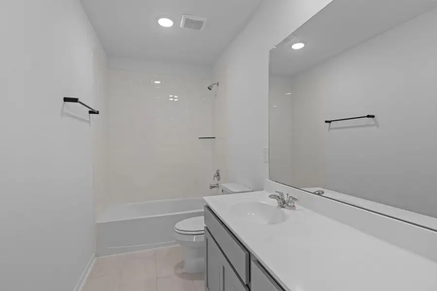 The secondary bath features tile flooring, white cabinetry and light countertops and a shower/tub combo. Perfect for accommodating any visiting family and friends.