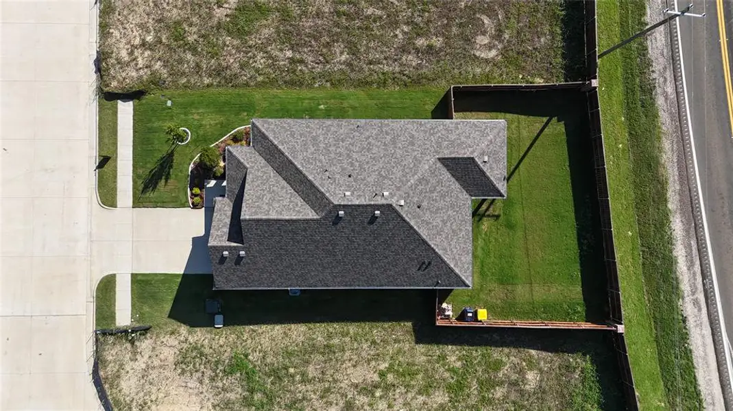 Gabled roofline residence featuring a gray shingle roof, concrete driveway, concrete sidewalk, fenced backyard, and a manicured lawn Gabled roofline residence featuring a gray shingle roof, concrete driveway, concrete sidewalk, fenced backyard, and a manicured lawn