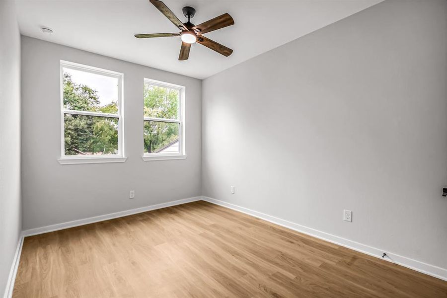 Large windows overlooking the front yard make this bedroom bright with natural light.