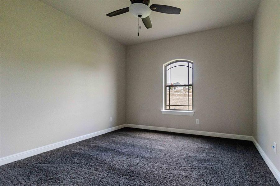 Carpeted empty room featuring ceiling fan