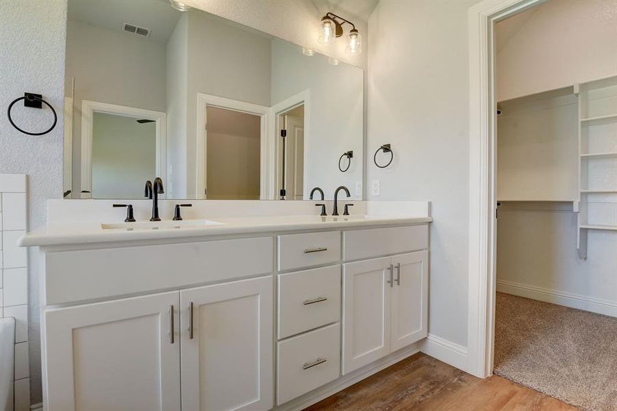 Bathroom with wood-type flooring, double sink, and large vanity