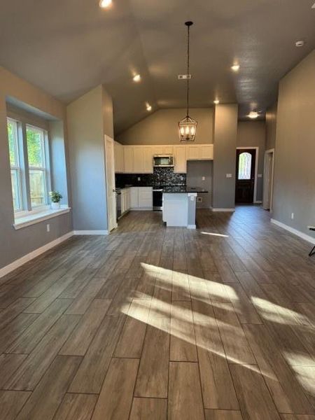 Kitchen featuring decorative light fixtures, dark hardwood / wood-style flooring, white cabinetry, and tasteful backsplash