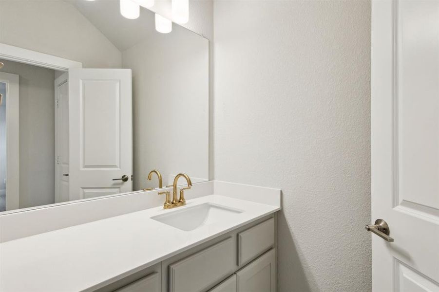 Bathroom with vanity, lofted ceiling, and a textured wall