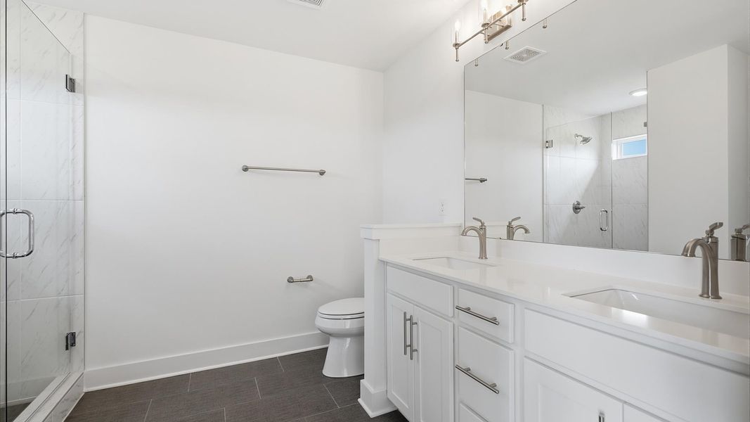 Highly functional and elegant en-suite with dual vanities, tiled walk-in shower, and refined finishes by DRB Homes